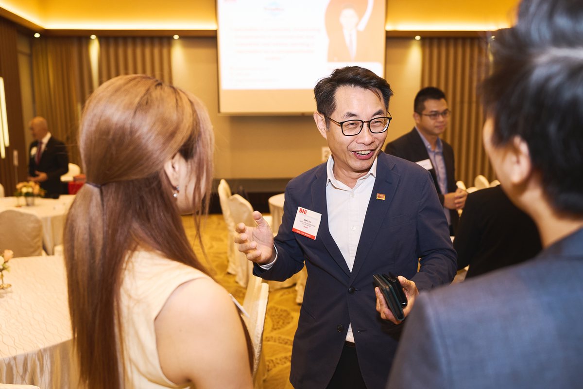 A member talking with two other people over coffee before the meeting